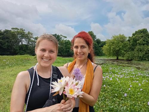 two women standing in a field holding flowers at Wilpattu Buma Lodge in Pahala Maragahawewa