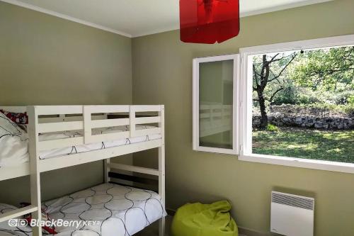 a bedroom with two bunk beds and a window at Belle maison avec piscine et terrain entièrement clôturé in Saint-Privat-de-Champclos