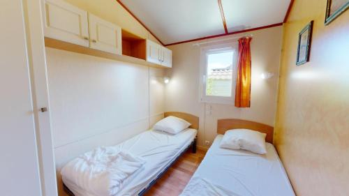 deux lits dans une petite pièce avec une fenêtre dans l'établissement Le Chalet de L Auzance - Piscine & Plage, à Brem-sur-Mer