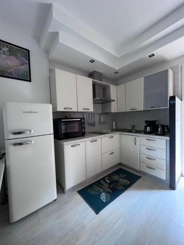 une cuisine avec des armoires blanches et un réfrigérateur blanc dans l'établissement Apartment, Favone, Corse du Sud, plage 50m, à Sari-Solenzara