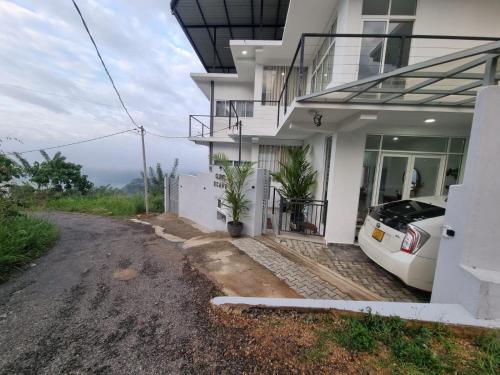a white house with a car parked outside of it at Cloudscape villa peradeniya in Gelioya