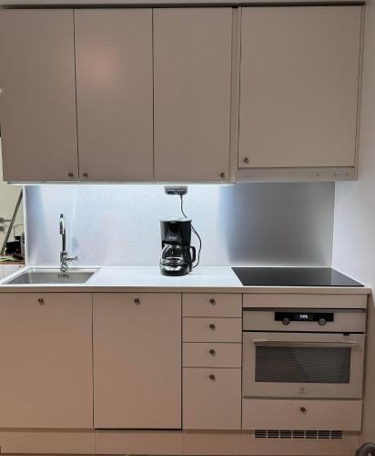 a kitchen with white cabinets and a sink at Modern Apartment in Helsinki metropolitan area in Espoo