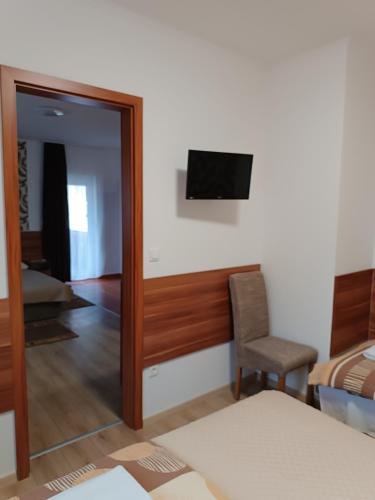 a room with a mirror and a tv and a chair at Boglárka Vendégház in Mosonmagyaróvár