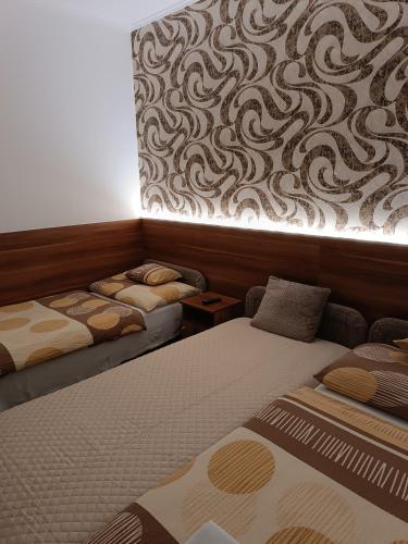 a room with two beds and a wall with a mural at Boglárka Vendégház in Mosonmagyaróvár