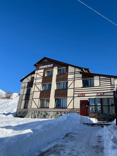 a building in the snow with a pile of snow at Soncho Gudauri in Gudauri