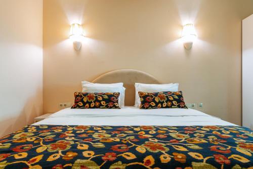 a bed with two pillows and two lights on the wall at Nekresi Estate in Kvareli