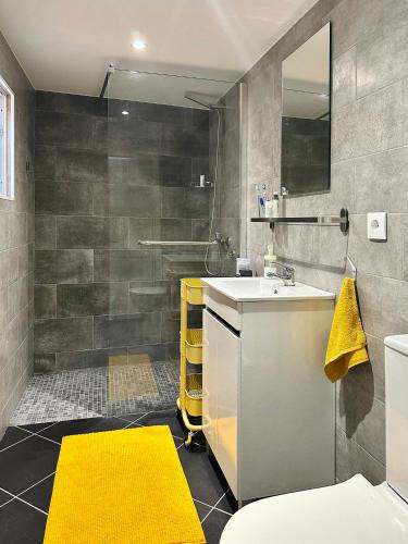 a bathroom with a sink and a yellow rug at Villa Tangerinetta in Ribeira das Tainhas