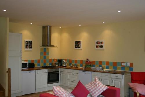 - une cuisine avec des placards blancs et du carrelage coloré au mur dans l'établissement Argein, à Villautou