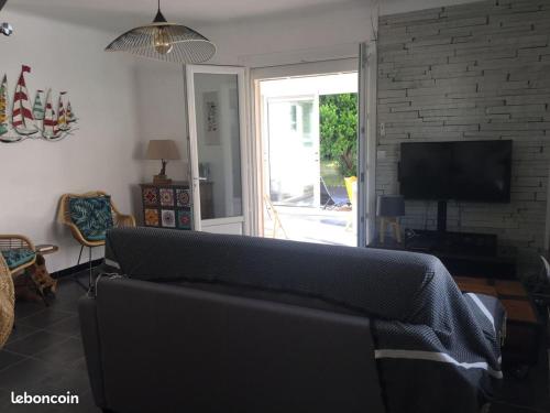 un salon avec un canapé et une télévision dans l'établissement Maison du bois, à Andernos-les-Bains