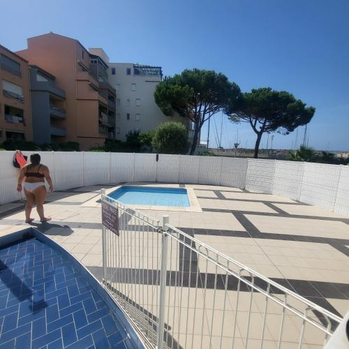 une femme se tient à côté d'une piscine dans l'établissement Appartement Cap D'Agde le Pharo, au Cap d'Agde