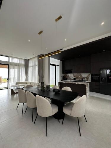 a dining room with a black table and white chairs at Villa Golf Novaworld in Bình Sum