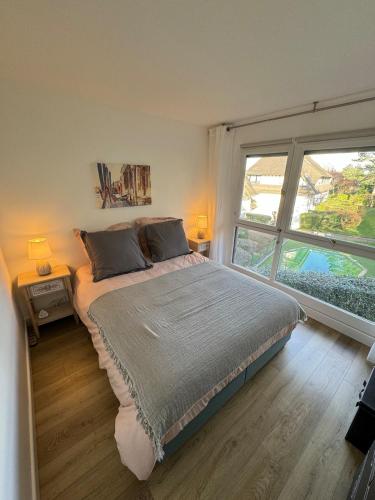 une chambre avec un grand lit et une grande fenêtre dans l'établissement 4 pieces 80m2, plage 7 mn a pied, parking gratuit, à Benerville-sur-Mer