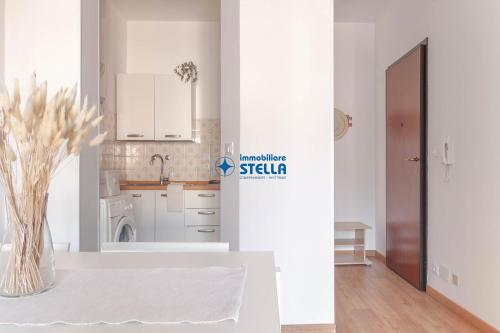 kuchnia z białymi szafkami i wazonem kwiatów na stole w obiekcie Condominio International w mieście Lido di Jesolo