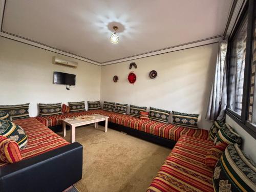 a living room with couches and a table in a room at Complexe Kariat Ayoub in Aït Zat