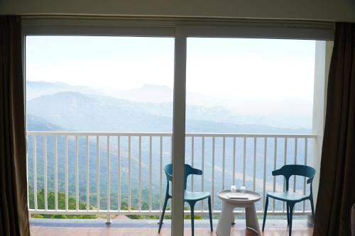 two chairs and a table on a balcony with a view at The Clouds End in Devikolam