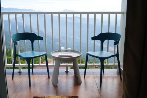 two chairs and a table on a balcony with a view at The Clouds End in Devikolam