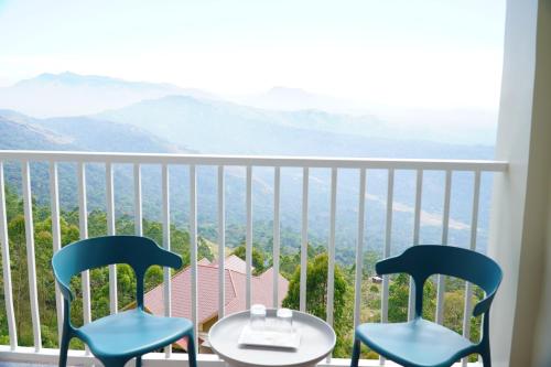 two chairs and a table on a balcony with a view at The Clouds End in Devikolam