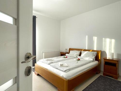una camera da letto con un letto con lenzuola e cuscini bianchi di Bella Vista Green Apartment a Braşov