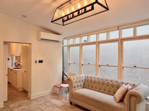 Una sala de estar con un sofá y grandes ventanales. en Kent St Townhouse, en Sídney