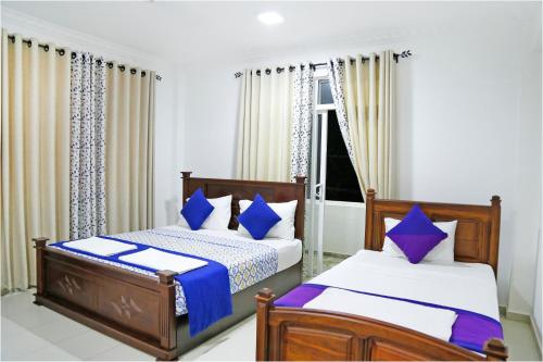 a bedroom with two beds with blue and white pillows at Ronaka Airport Transit Hotel in Katunayake