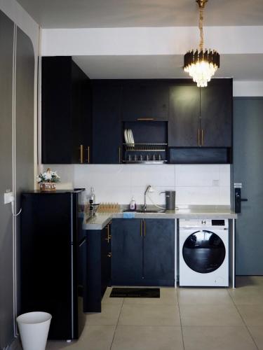 a kitchen with black cabinets and a dishwasher at Free Netflix Soho at Meta City for 2 Pax in Seri Kembangan