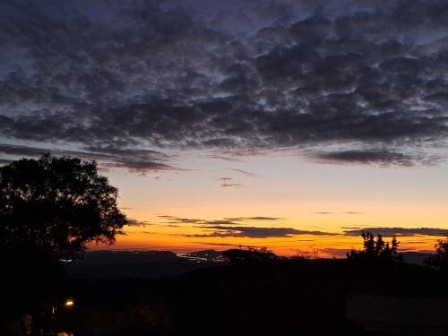 a sunset from a hill with a tree in the foreground at למרפסת La Balcona in Chorazim