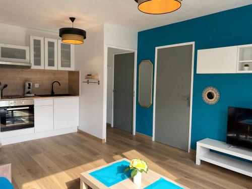 un salon avec un mur d'accent bleu dans l'établissement Bel appartement côté Port avec Piscine & Tennis proche Plage, à Saint Cyprien Plage