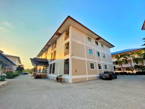 een gebouw met een auto geparkeerd op een parkeerplaats bij Jaroon House in Samutprakarn