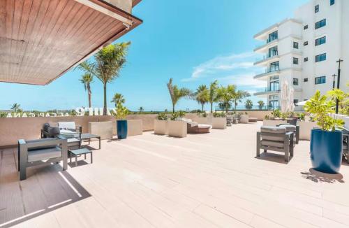 a patio with tables and benches and a building at Luxury Retreat Condo 3BR Pool & Spa Azzure-Cap Cana in Punta Cana