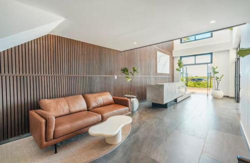 a living room with a brown leather couch and a table at Luxury Retreat Condo 3BR Pool & Spa Azzure-Cap Cana in Punta Cana