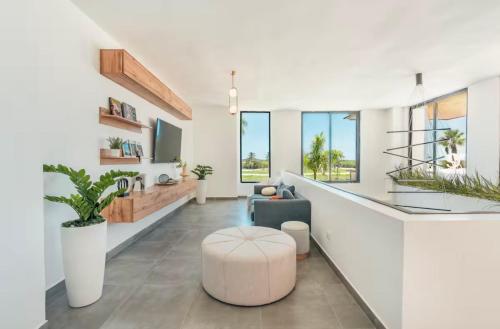 a white living room with a couch and a stool at Luxury Retreat Condo 3BR Pool & Spa Azzure-Cap Cana in Punta Cana
