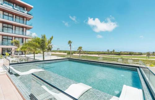a swimming pool with chairs and a building at Luxury Retreat Condo 3BR Pool & Spa Azzure-Cap Cana in Punta Cana