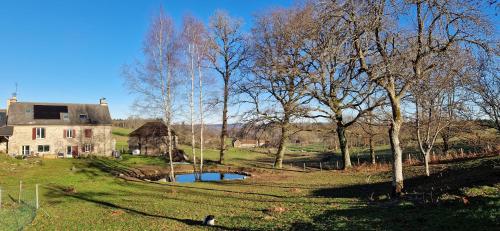 a house and a pond in a field with trees at O Fil de l'hôte in Saint-Yrieix-la-Montagne