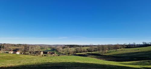 a green field with trees in the distance at O Fil de l'hôte in Saint-Yrieix-la-Montagne