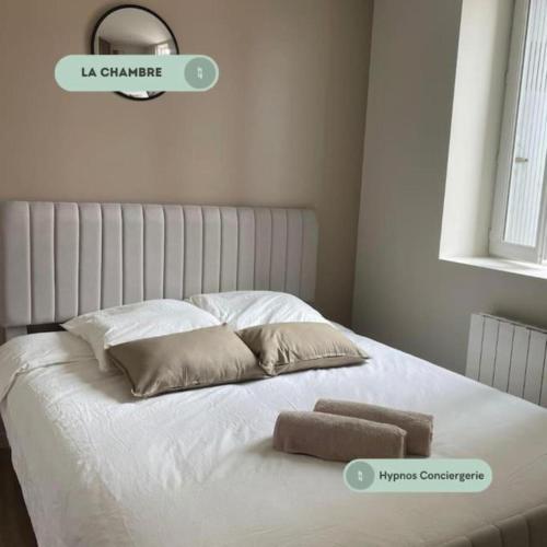 un lit blanc avec deux oreillers dessus dans l'établissement Le capucin, départ Saint Jacques, au Puy-en-Velay