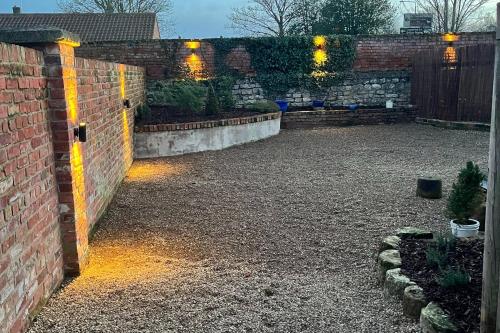 a backyard with a brick wall and lights on it at Torworth - 1 Bed Barn - Sleeps 3 - Hot Tub in Torworth