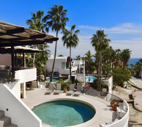 a pool at a resort with palm trees and the ocean at Apartment near the beach with terrace #10 in Cabo San Lucas