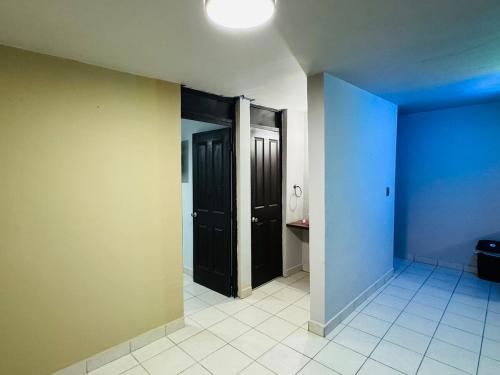 an empty hallway with two black doors and a tile floor at Casa Sonora Dunas Secure Parking in San Luis Río Colorado