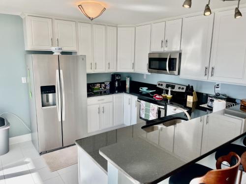 a kitchen with white cabinets and a stainless steel refrigerator at Big Waterfront House with Amazing View and Swim Deck home in Norfolk