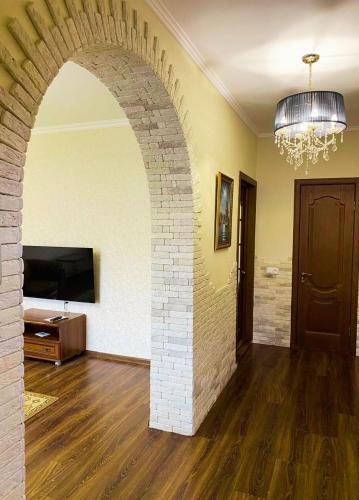 a living room with a brick archway and a television at Будинок з Терасою Біля Фонтанів in Umanʼ