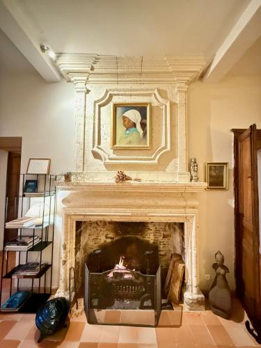 a living room with a fireplace with a painting above it at Chambres d'hôtes au Château de Gandillac in Saint-Martial-Viveyrol