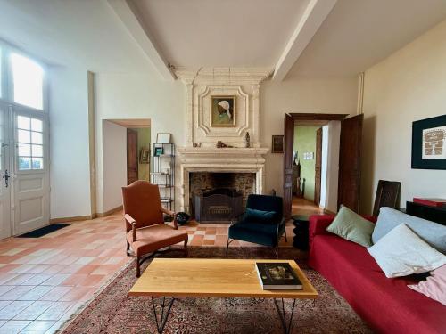a living room with a red couch and a fireplace at Chambres d'hôtes au Château de Gandillac in Saint-Martial-Viveyrol