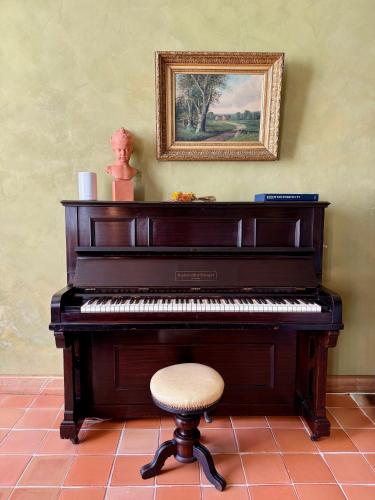 a piano with a stool and a picture on the wall at Chambres d'hôtes au Château de Gandillac in Saint-Martial-Viveyrol