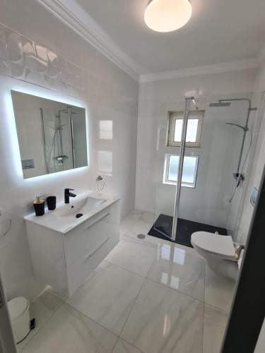 a white bathroom with a sink and a toilet at VILLA DO LIMAO in Tavira