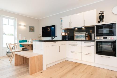 a kitchen with white cabinets and a wooden table at KÖ-Gartensuite in Westerland
