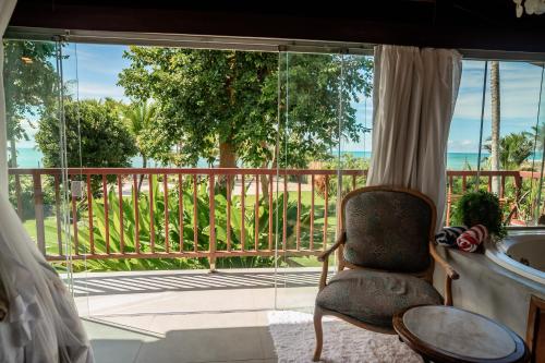 a room with a chair and a large window at Pousada Villa Tainá - Arraial d'Ajuda, Bahia in Arraial d'Ajuda