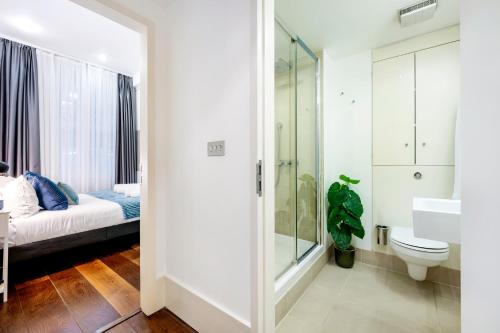 a bathroom with a bed and a sink and a toilet at Welcome London Mayfair in London