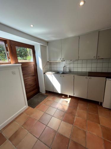a kitchen with white cabinets and a tile floor at Centralt værelse med bad og køkken in Herning