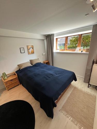 a bedroom with a large blue bed with a window at Centralt værelse med bad og køkken in Herning