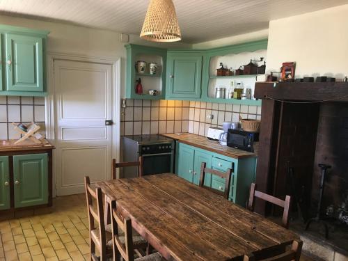 une cuisine avec des placards verts et une table en bois dans l'établissement Clairefontaine, à Grigne